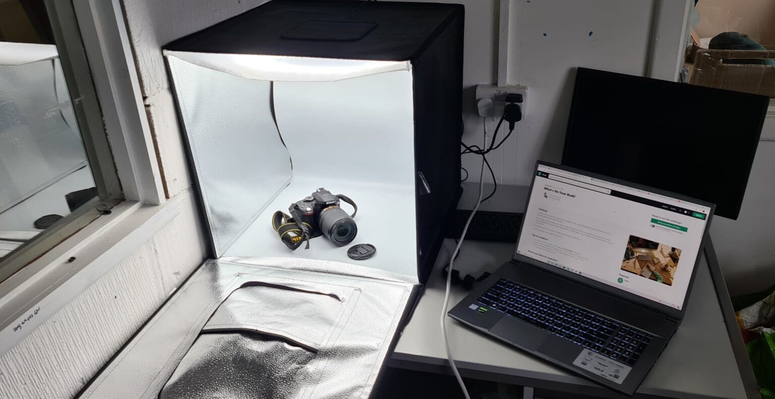 Fotostudio-opstelling met camera in een licht tent en laptop ernaast.