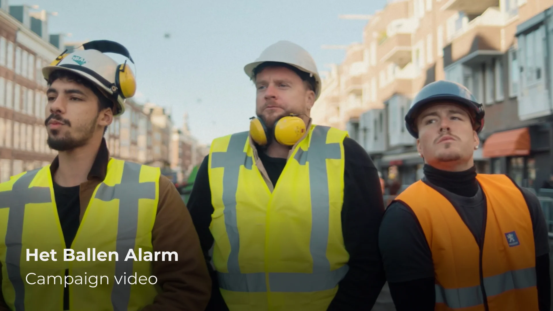 Drie bouwvakkers in fluorescerende hesjes kijken stoer de camera in